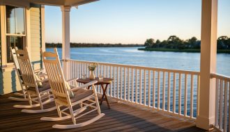 Rocking chairs on a riverside bed & breakfast porch overlooking the calm Manatee River in Palmetto, Florida at golden hour.