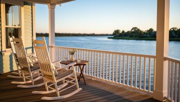Rocking chairs on a riverside bed & breakfast porch overlooking the calm Manatee River in Palmetto, Florida at golden hour.